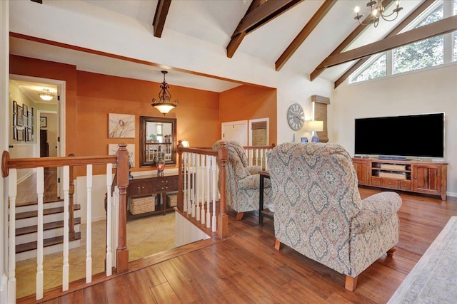 living area with a notable chandelier, beam ceiling, high vaulted ceiling, and wood finished floors