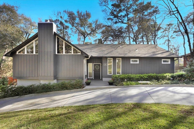 mid-century home with a front lawn and a chimney