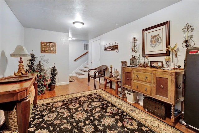 sitting room featuring visible vents, stairway, baseboards, and wood finished floors