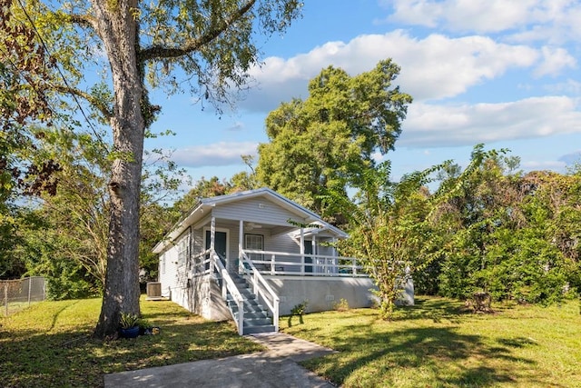 bungalow featuring a front lawn, covered porch, and central AC unit