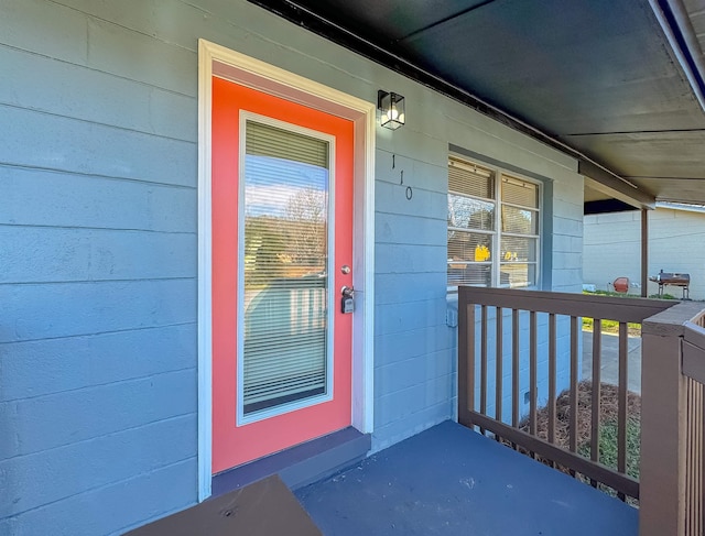 view of exterior entry featuring a porch and concrete block siding