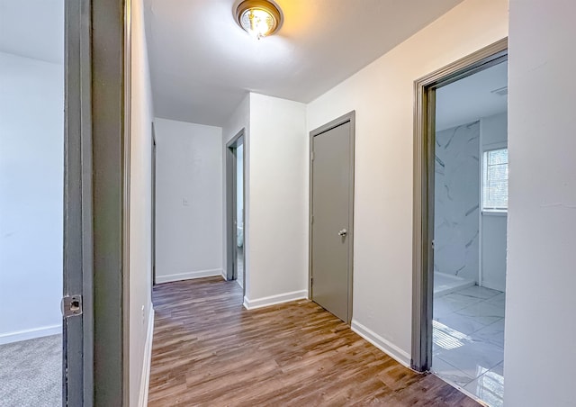 corridor with baseboards and wood finished floors
