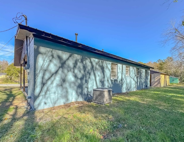 view of side of home featuring a lawn and central AC