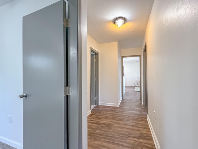 corridor featuring baseboards and wood finished floors