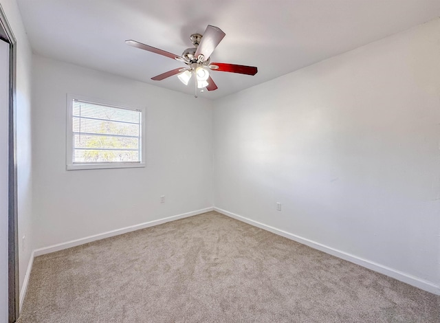 carpeted spare room featuring baseboards and a ceiling fan
