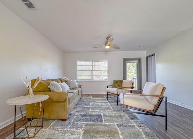 living area featuring visible vents, baseboards, a ceiling fan, and wood finished floors