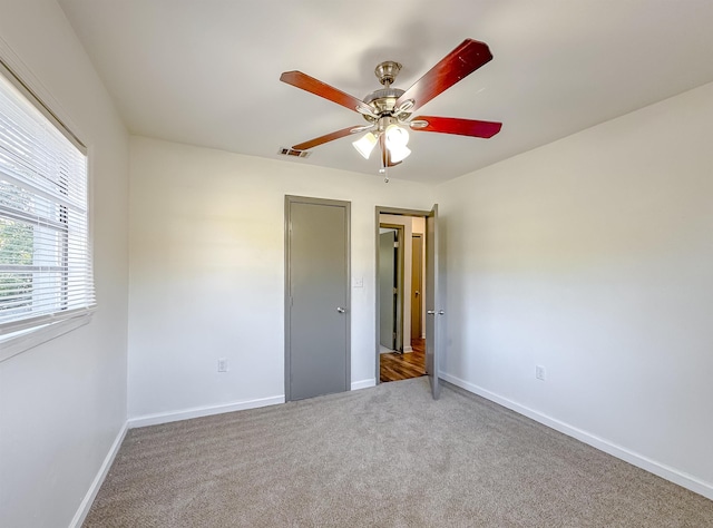 unfurnished bedroom with carpet flooring, visible vents, baseboards, and ceiling fan