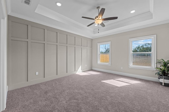 unfurnished bedroom featuring ornamental molding, light carpet, ceiling fan, and a tray ceiling