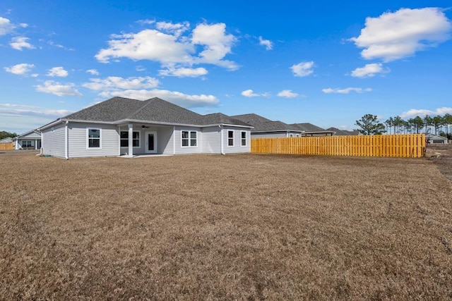 rear view of property with ceiling fan and a lawn