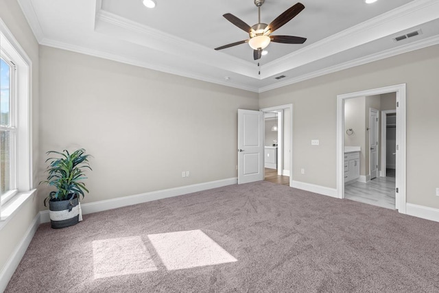 unfurnished bedroom featuring crown molding, ceiling fan, ensuite bathroom, a tray ceiling, and light colored carpet