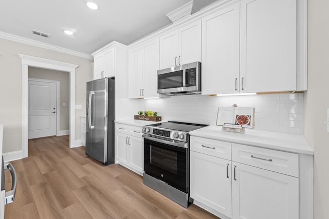 kitchen with white cabinetry, stainless steel appliances, crown molding, and light wood-type flooring