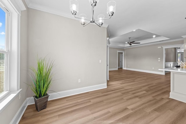 interior space featuring ornamental molding, plenty of natural light, a raised ceiling, and light wood-type flooring