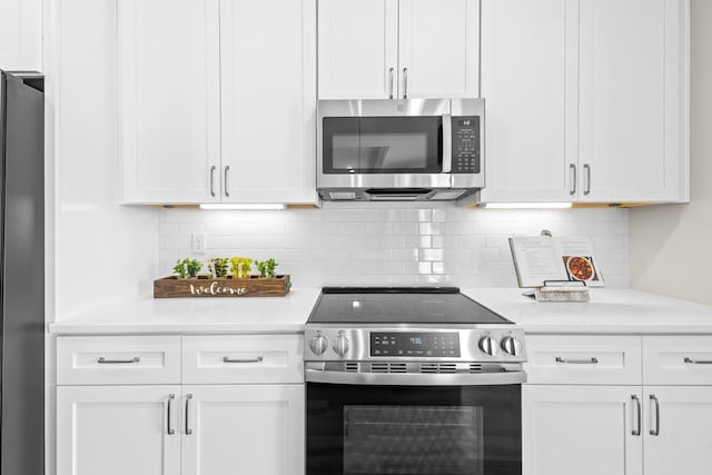 kitchen with backsplash, white cabinets, and appliances with stainless steel finishes