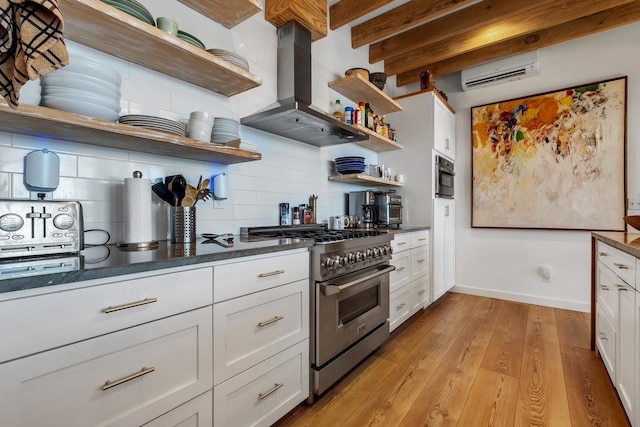 kitchen with island exhaust hood, white cabinetry, high end stainless steel range, and an AC wall unit