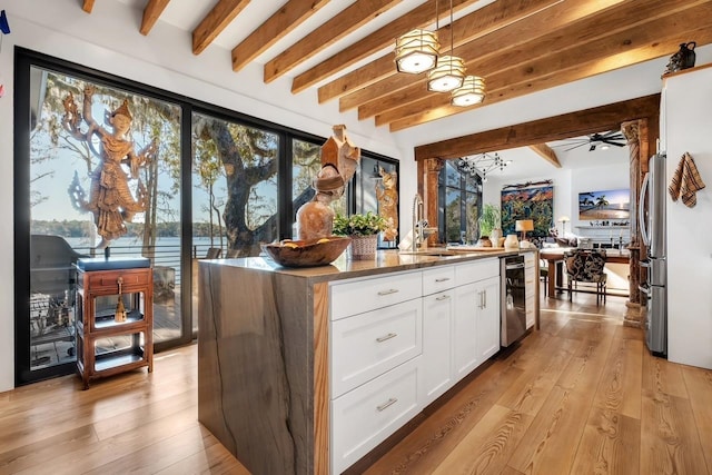 kitchen featuring beamed ceiling, decorative light fixtures, white cabinetry, and a kitchen island with sink