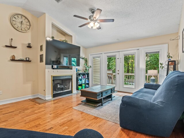 7214 Jaffrey Ct, Tallahassee, FL 32312 - living room featuring vaulted ceiling, a textured ceiling, a fireplace with flush hearth, wood finished floors, and ceiling fan