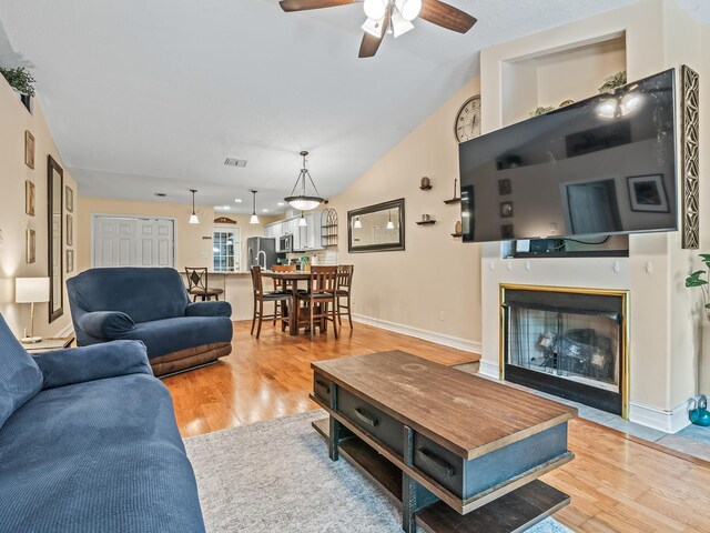 7214 Jaffrey Ct, Tallahassee, FL 32312 - living area featuring light wood-style floors, a ceiling fan, a fireplace with flush hearth, vaulted ceiling, and baseboards