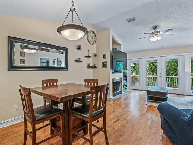 7214 Jaffrey Ct, Tallahassee, FL 32312 - dining area featuring light wood finished floors, a textured ceiling, baseboards, a ceiling fan, and a fireplace