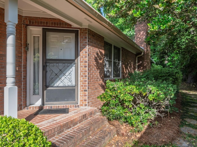property entrance with brick siding and a chimney