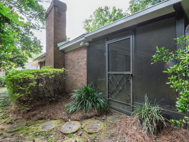 view of property exterior with brick siding and a chimney