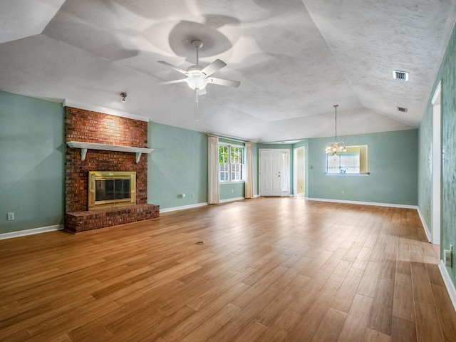 unfurnished living room featuring ceiling fan with notable chandelier, baseboards, lofted ceiling, and visible vents