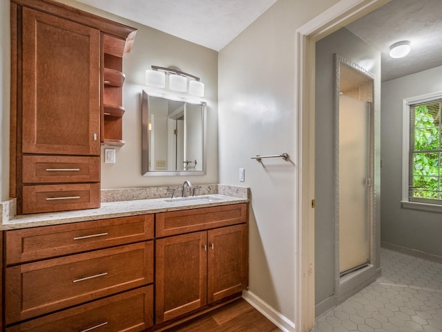bathroom featuring vanity, baseboards, and a stall shower