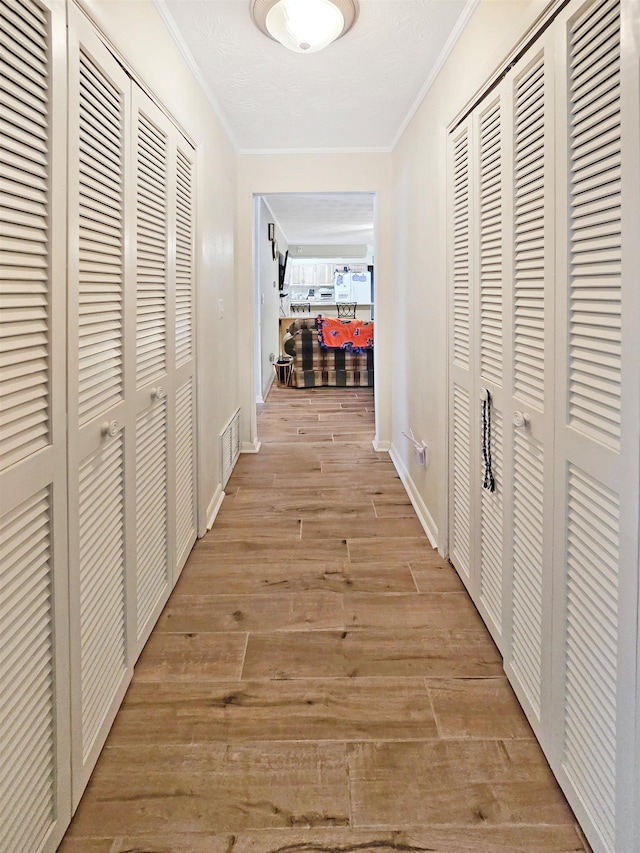 hall featuring ornamental molding and light hardwood / wood-style floors