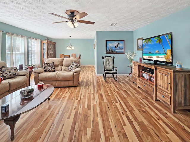 living room with ceiling fan, a textured ceiling, and light wood-type flooring