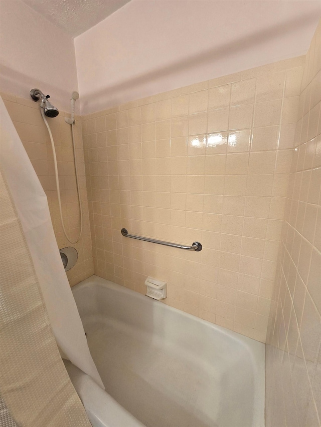 bathroom with shower / bathtub combination with curtain and a textured ceiling