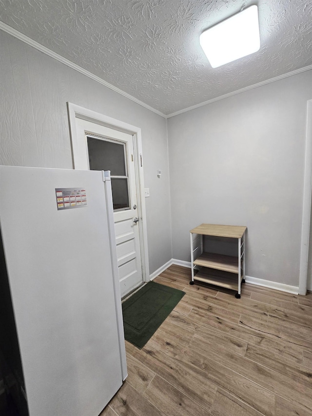 doorway featuring hardwood / wood-style flooring, ornamental molding, and a textured ceiling