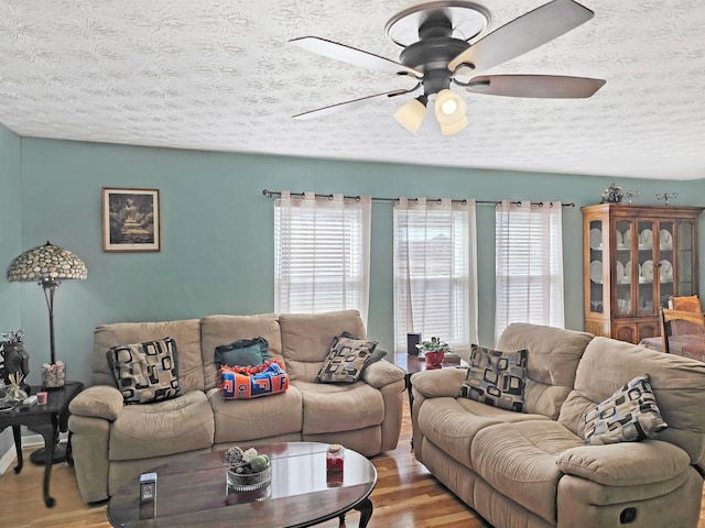 living room with hardwood / wood-style floors, a textured ceiling, and ceiling fan