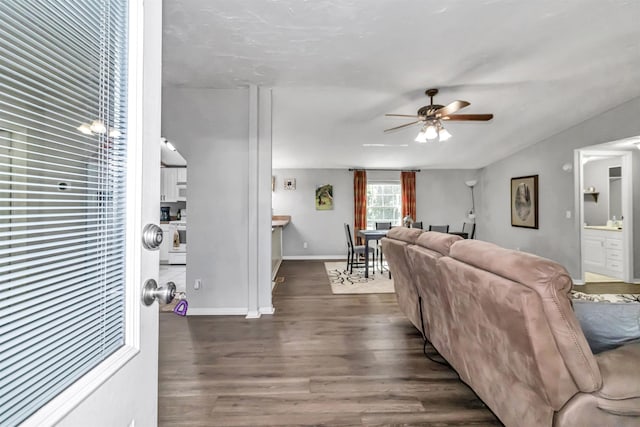 living room featuring dark wood-style floors, ceiling fan, and baseboards