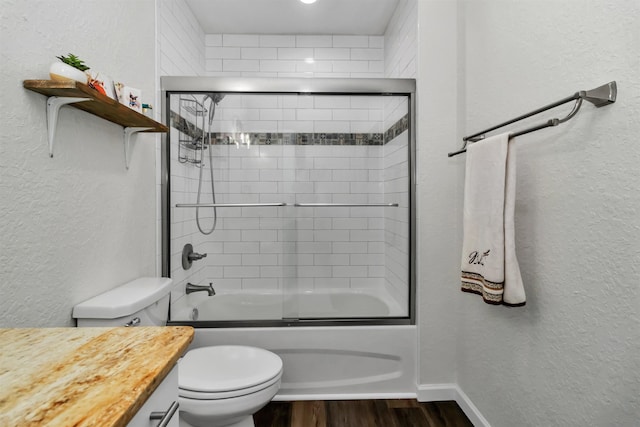 full bathroom featuring a textured wall, toilet, enclosed tub / shower combo, vanity, and wood finished floors