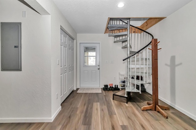 entryway featuring electric panel, a textured ceiling, baseboards, and wood finished floors