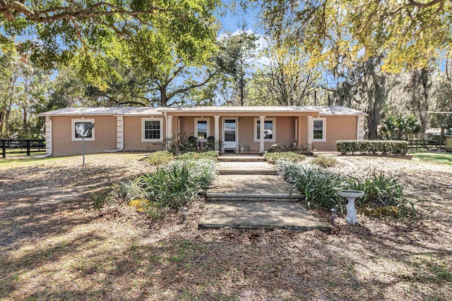 ranch-style home featuring covered porch, fence, and stucco siding