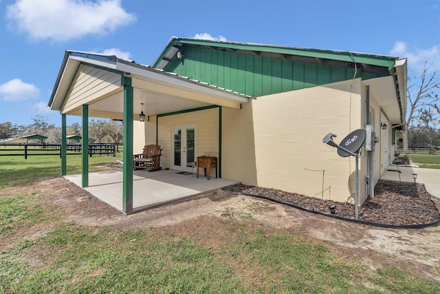 rear view of house featuring concrete block siding, a patio area, fence, and french doors