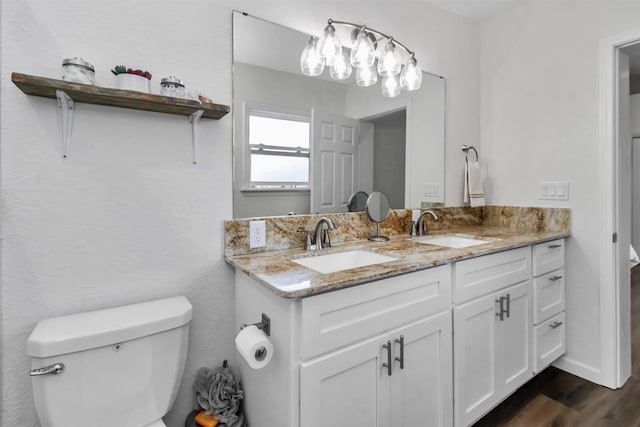 bathroom featuring double vanity, wood finished floors, a sink, and toilet