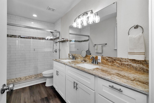 full bathroom with double vanity, visible vents, a sink, and wood finished floors