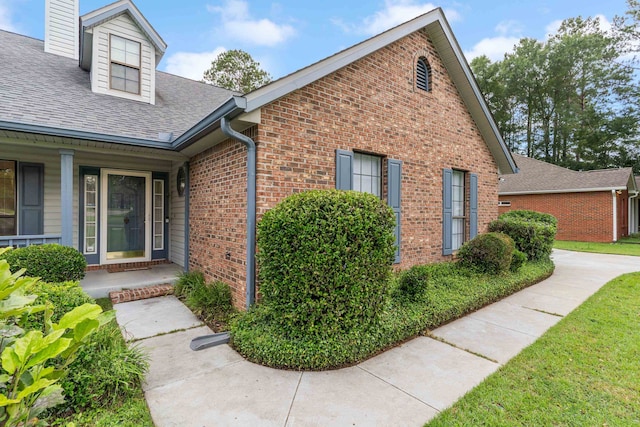 1989 Setting Sun Trl, Tallahassee, FL 32303 - view of side of property featuring roof with shingles, brick siding, a chimney, and a porch