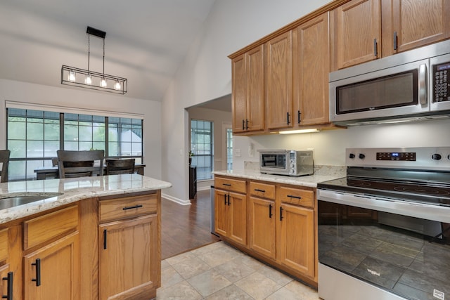 1989 Setting Sun Trl, Tallahassee, FL 32303 - kitchen with stainless steel appliances, lofted ceiling, light stone counters, hanging light fixtures, and brown cabinets