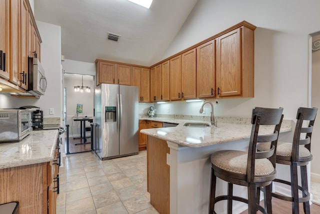 1989 Setting Sun Trl, Tallahassee, FL 32303 - kitchen with stainless steel appliances, a peninsula, light stone counters, a kitchen breakfast bar, and lofted ceiling