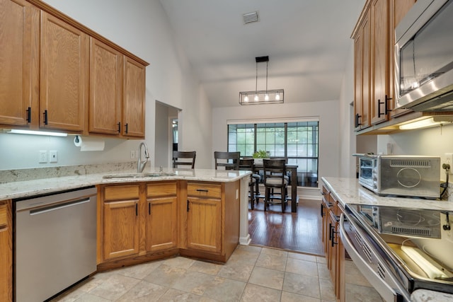 1989 Setting Sun Trl, Tallahassee, FL 32303 - kitchen featuring stainless steel appliances, a peninsula, vaulted ceiling, brown cabinets, and light stone counters