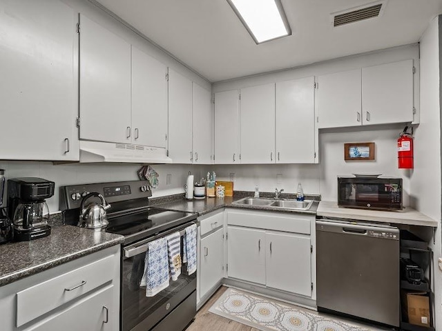 12 Lake Essay Dr, Panacea, FL 32346 - kitchen featuring under cabinet range hood, appliances with stainless steel finishes, a sink, white cabinets, and dark countertops