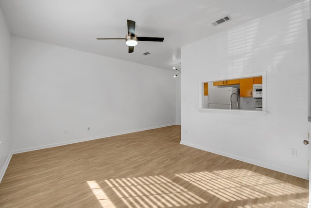 unfurnished living room with ceiling fan, visible vents, light wood-style flooring, and baseboards