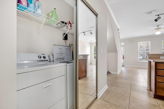 clothes washing area with ornamental molding, light tile patterned floors, and washer and dryer