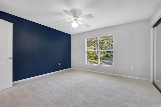 carpeted spare room featuring ceiling fan