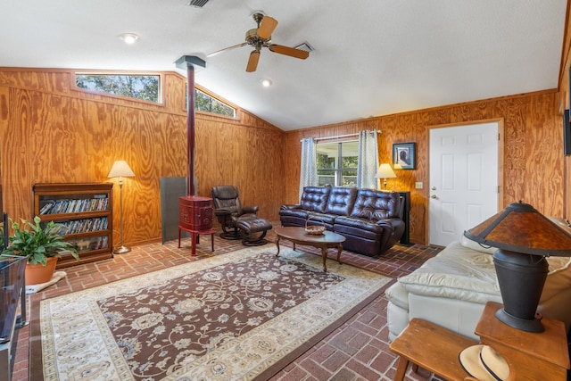 living room with brick floor, vaulted ceiling, wood walls, and ceiling fan