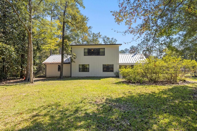 rear view of property with a lawn, a standing seam roof, and metal roof