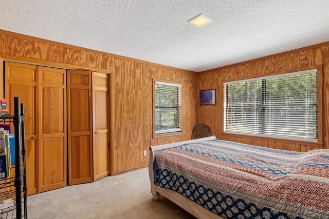 bedroom with a textured ceiling, wood walls, and light carpet