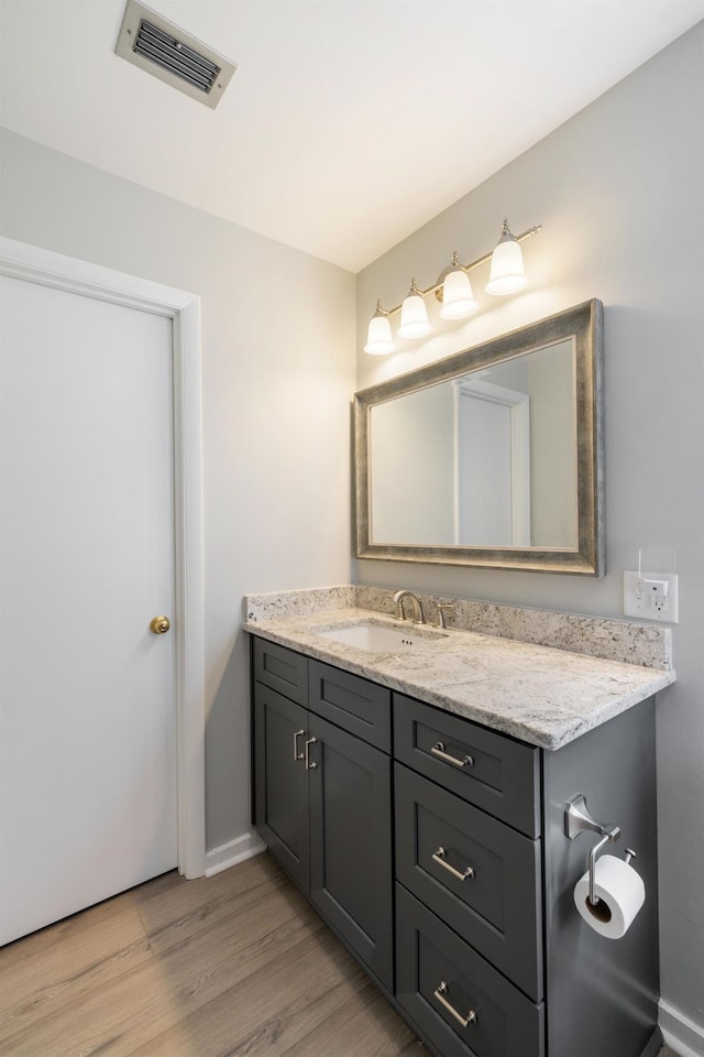 bathroom with baseboards, wood finished floors, visible vents, and vanity